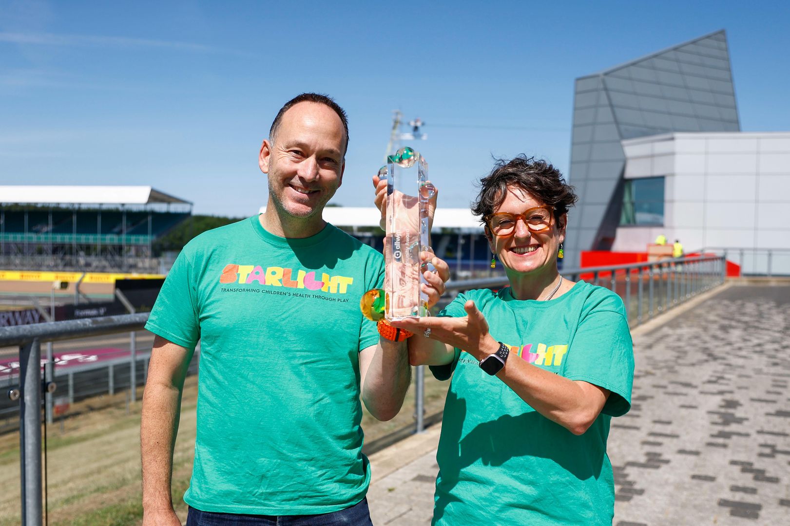 Jonny Wright, Director of Income Generation and Engagement and Laura Walsh, Director of Play in Healthcare, accept the F1® Allwyn Global Community Award on behalf of Starlight Children’s Foundation.